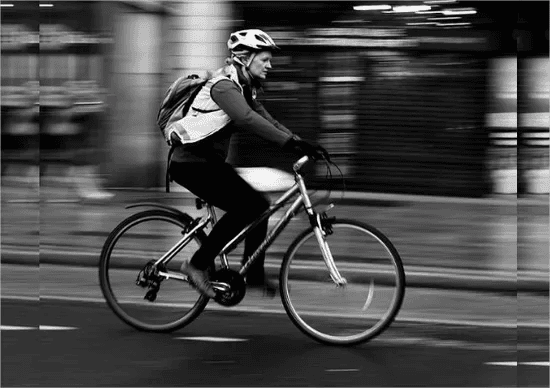 Black and white blurred photograph of a woman biking.